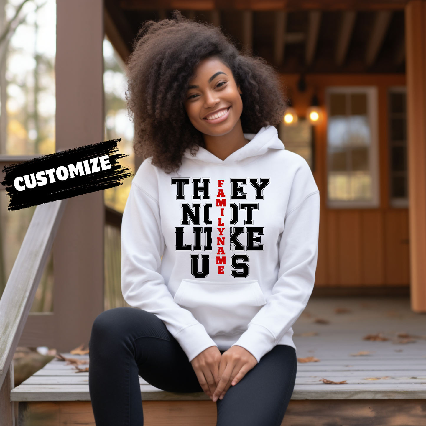 Person wearing a white hoodie with text, sitting on a wooden deck.  Family Reunion Hoodie - They Not Like Us - Custom Family Name Matching Hoodie