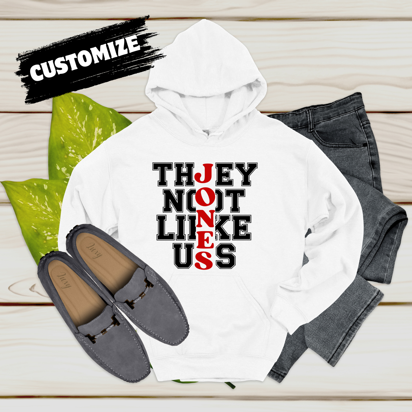 White hoodie with text, gray loafers, and jeans on a wooden surface with 'Customize' text.  Family Reunion Hoodie - They Not Like Us - Custom Family Name Matching Hoodie