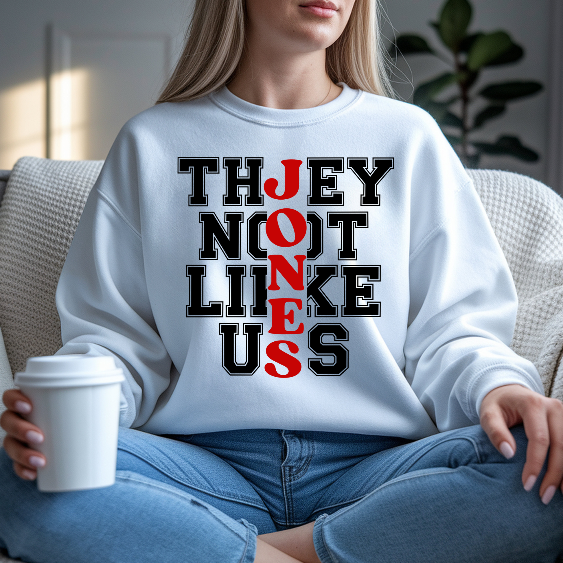 Person wearing a white sweatshirt with a unique text design, sitting on a couch holding a cup.  CUSTOMIZE