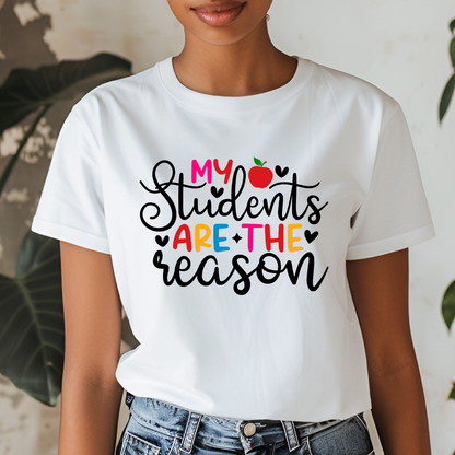 A woman wearing a white graphic t-shirt with the text 'My Students Are The Reason' in black and colorful lettering, paired with blue jeans.