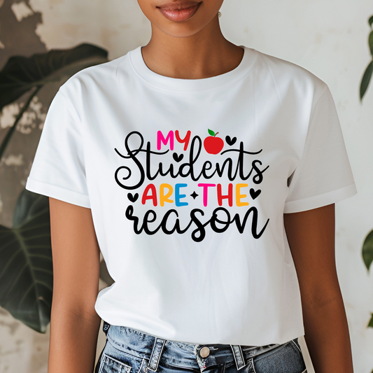 A woman wearing a white graphic t-shirt with the text 'My Students Are The Reason' in black and colorful lettering, paired with blue jeans.