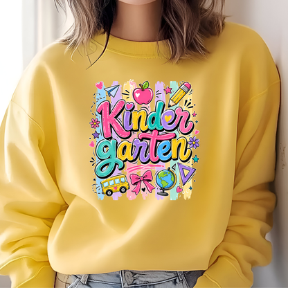 A person wearing a bright yellow crewneck sweatshirt with a colorful 'Kinder Garten' graphic on the chest, paired with light blue jeans.