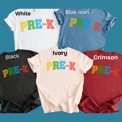 Five graphic t-shirts in different colors are displayed on a solid teal background, each labeled with its color name (White, Blue Jean, Black, Ivory, Crimson) above the shirt. The shirts feature a colorful 'PRE-K' text graphic across the chest.