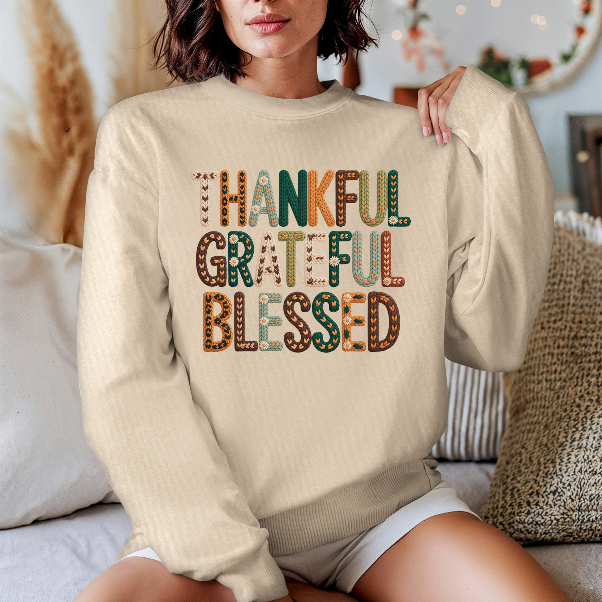 Person wearing a beige sweatshirt with 'Thankful, Grateful, Blessed' text in colorful letters.