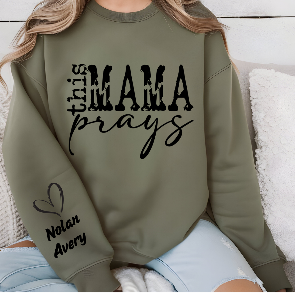 Women wearing This mama prays olive green sweater emphasing a praying mama, a spiritual mama, a religious mama Sweatshirt with personalized children's name on the sleeve

