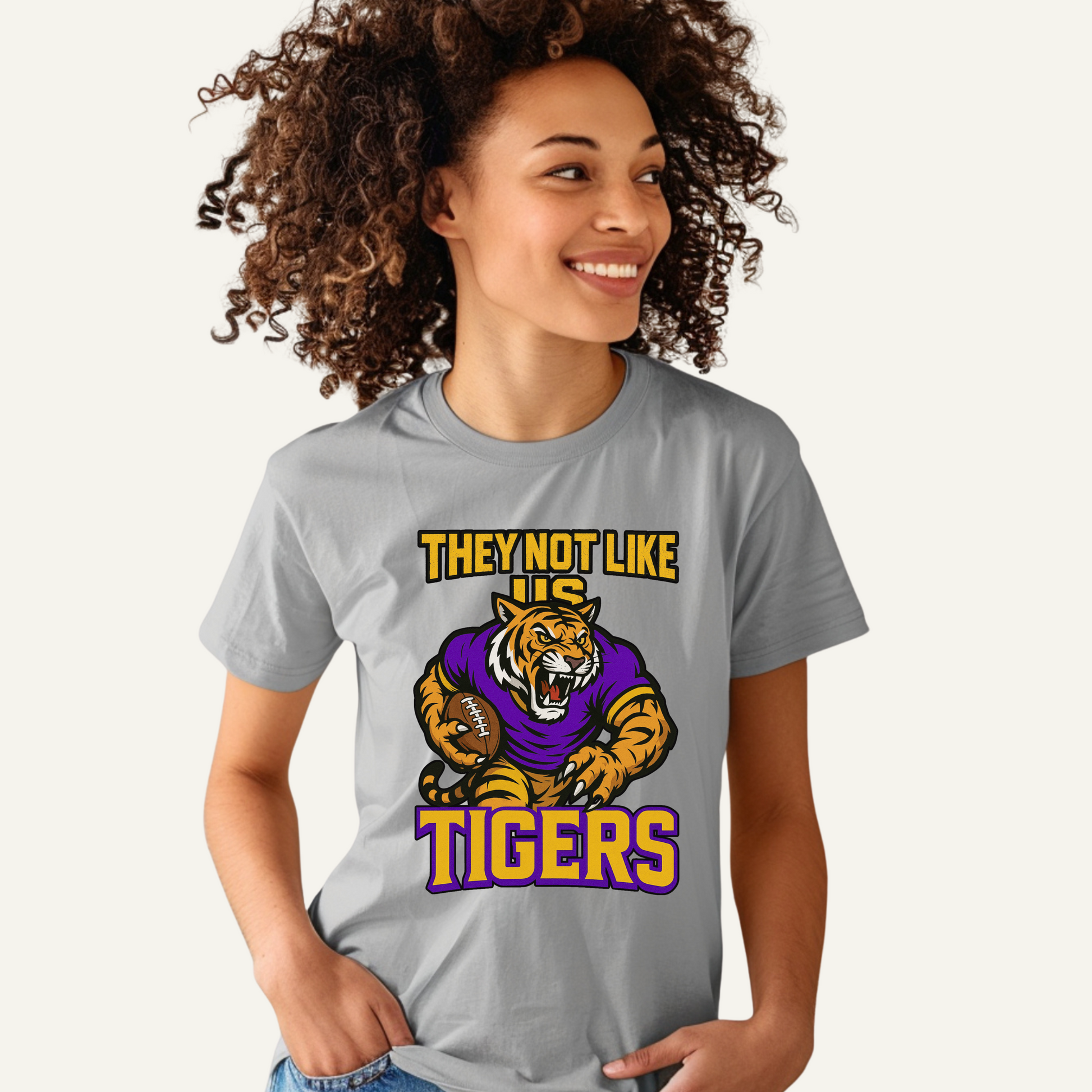 Person wearing a gray t-shirt with a tiger graphic and text on a white background Tigers Mascot Shirt - Bold Tigers They Not Like Us Game Day Spirit Tee