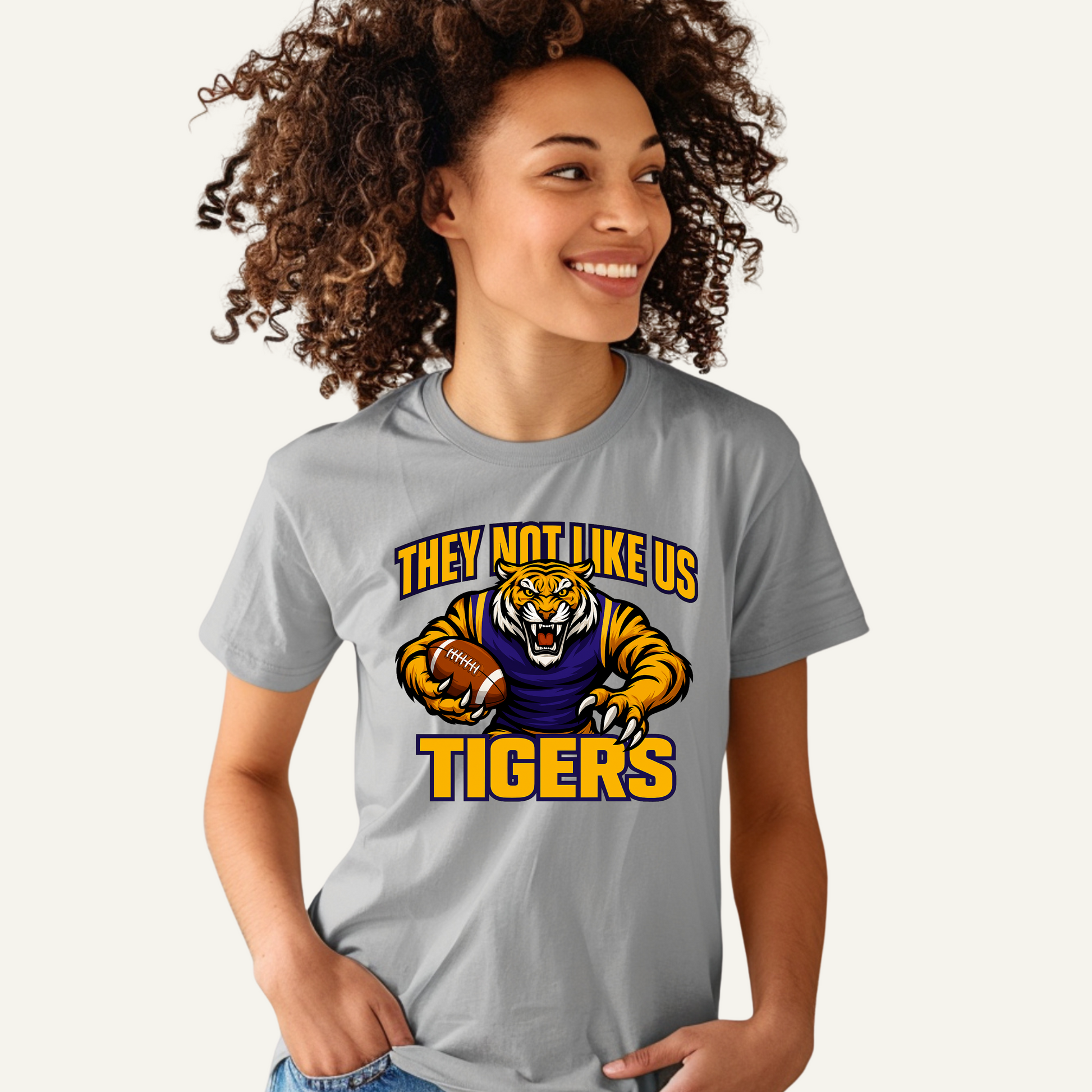 Person wearing a gray t-shirt with a tiger graphic and text on a white background Tigers Mascot T-shirt - Tigers They Not Like Us Game Day Spirit Tee