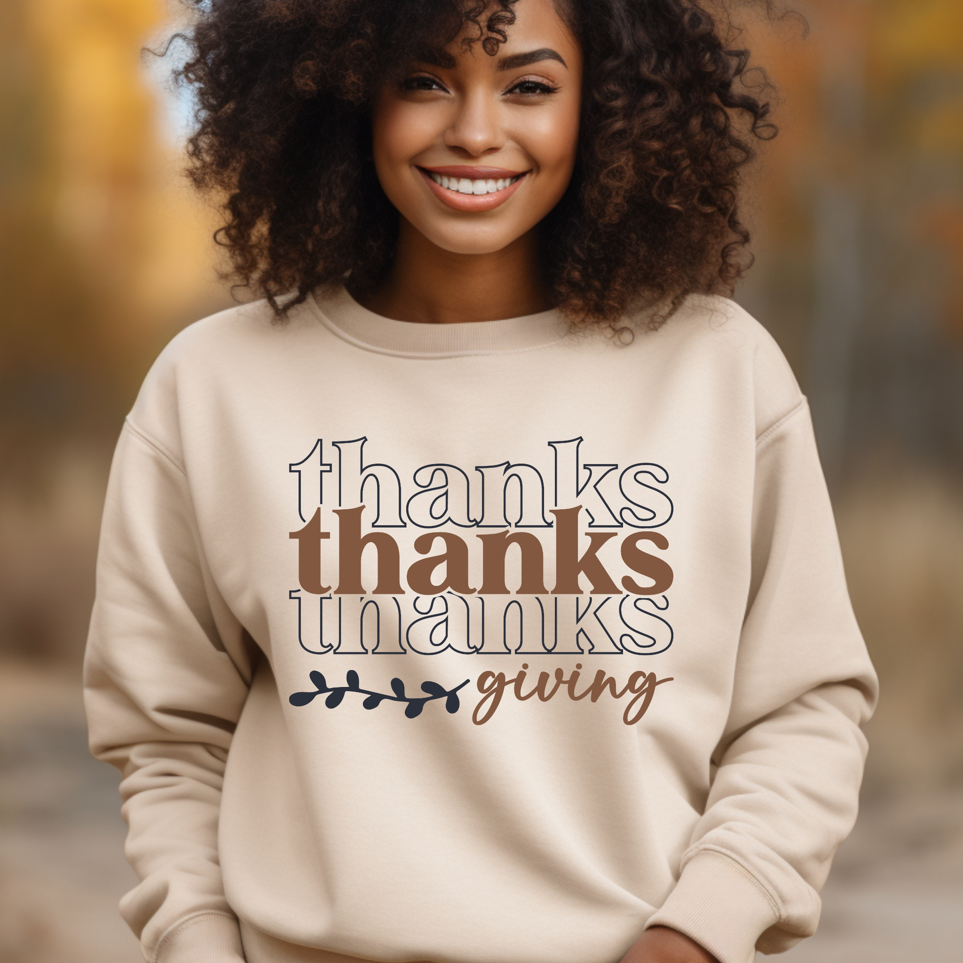 Person wearing a beige sweatshirt with 'thanks thanks thanks giving' text in an outdoor setting.