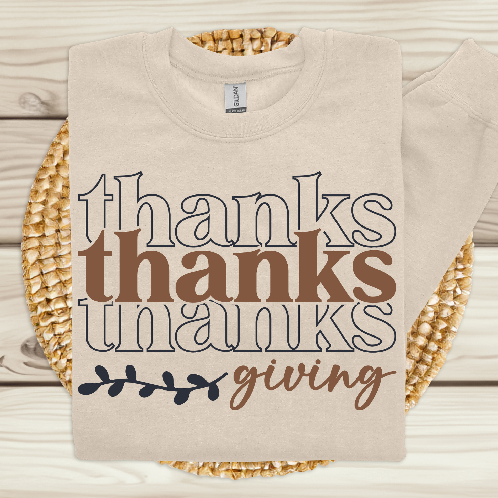 Beige sweatshirt with 'thanks thanks giving' text on a wooden surface