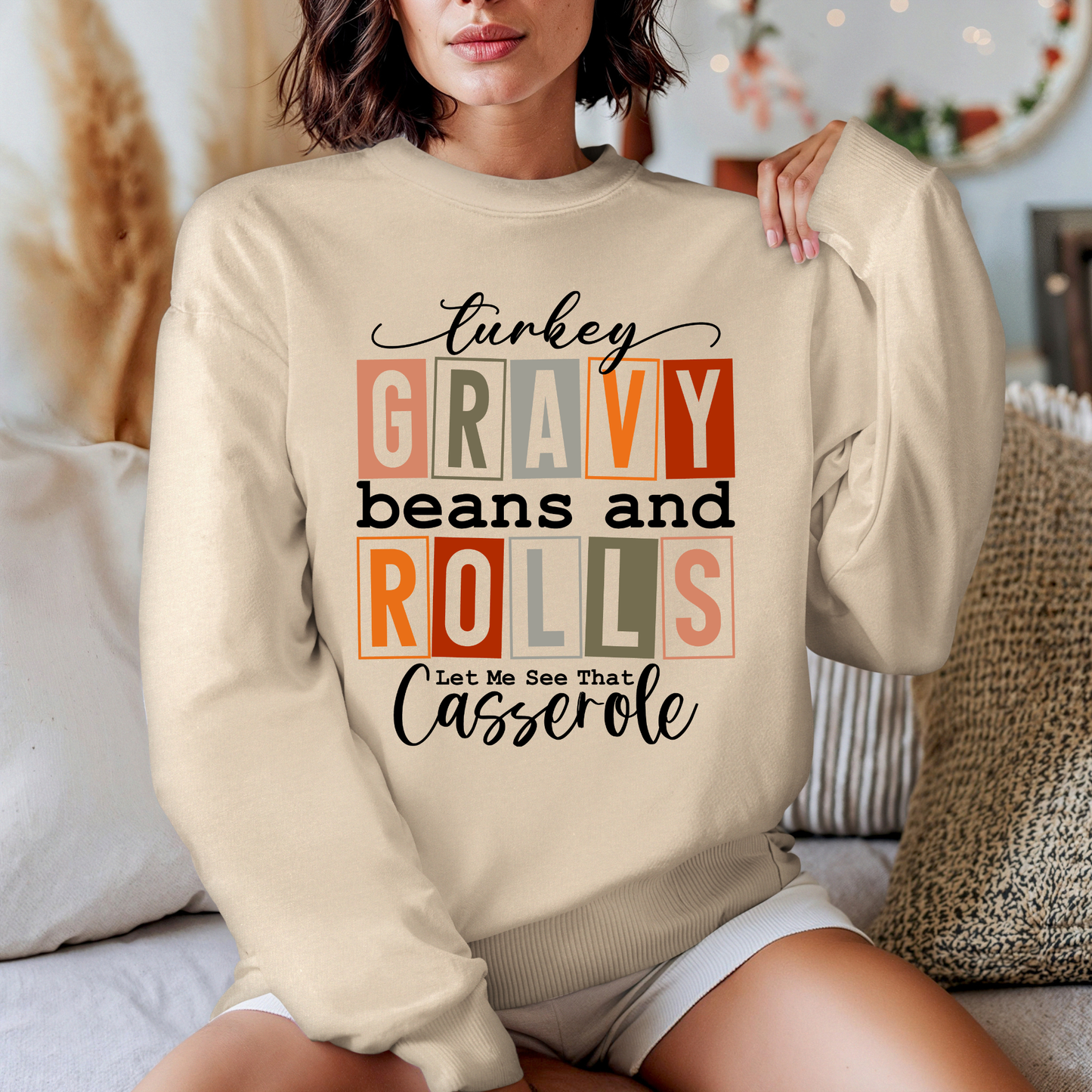 Person wearing a beige sweatshirt with text design sitting on a couch.