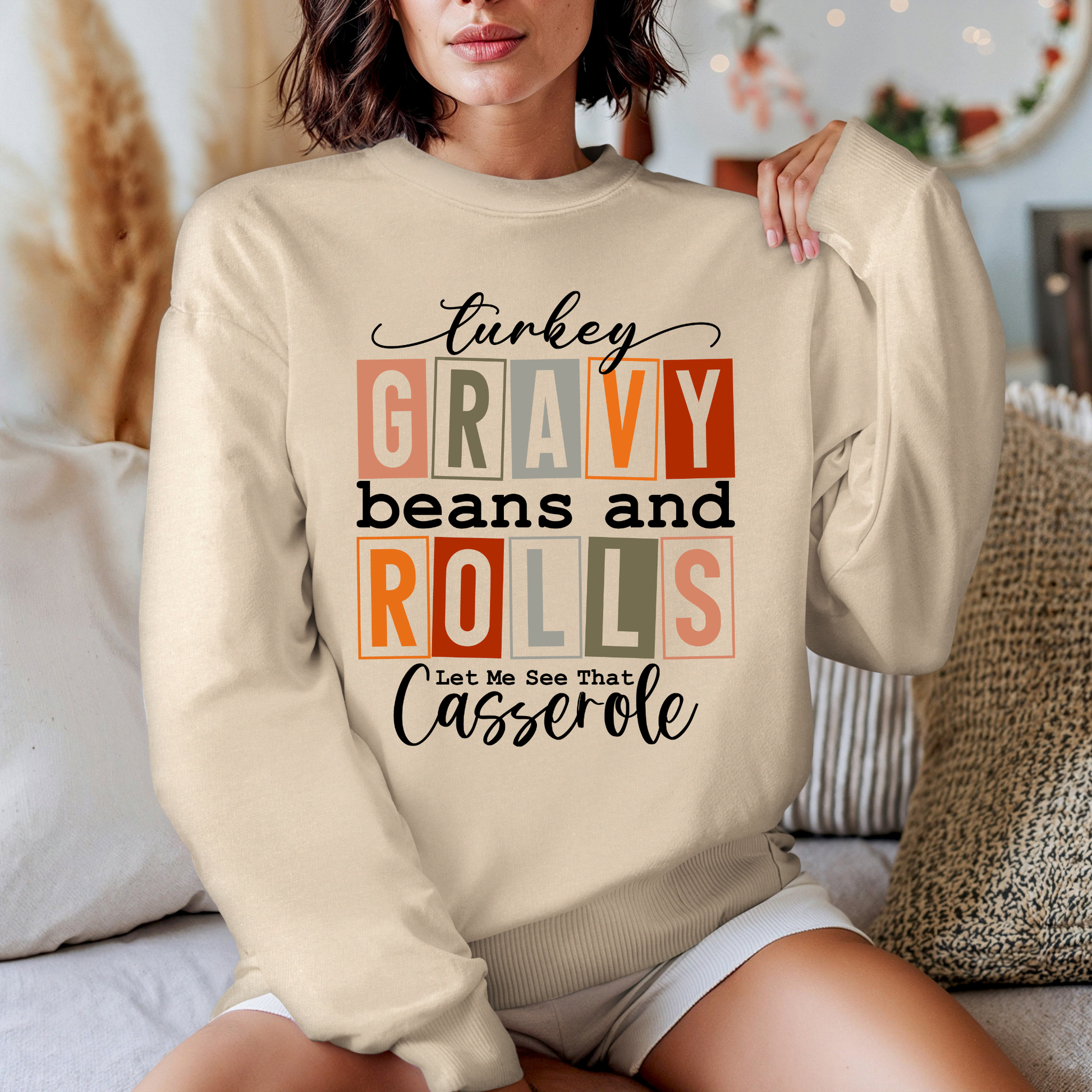 Person wearing a beige sweatshirt with text design sitting on a couch.