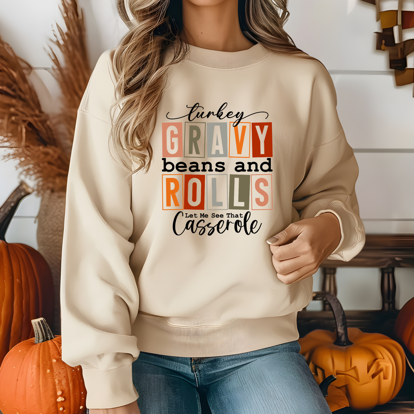 Person wearing a beige sweatshirt with humorous text design in a festive setting with pumpkins.