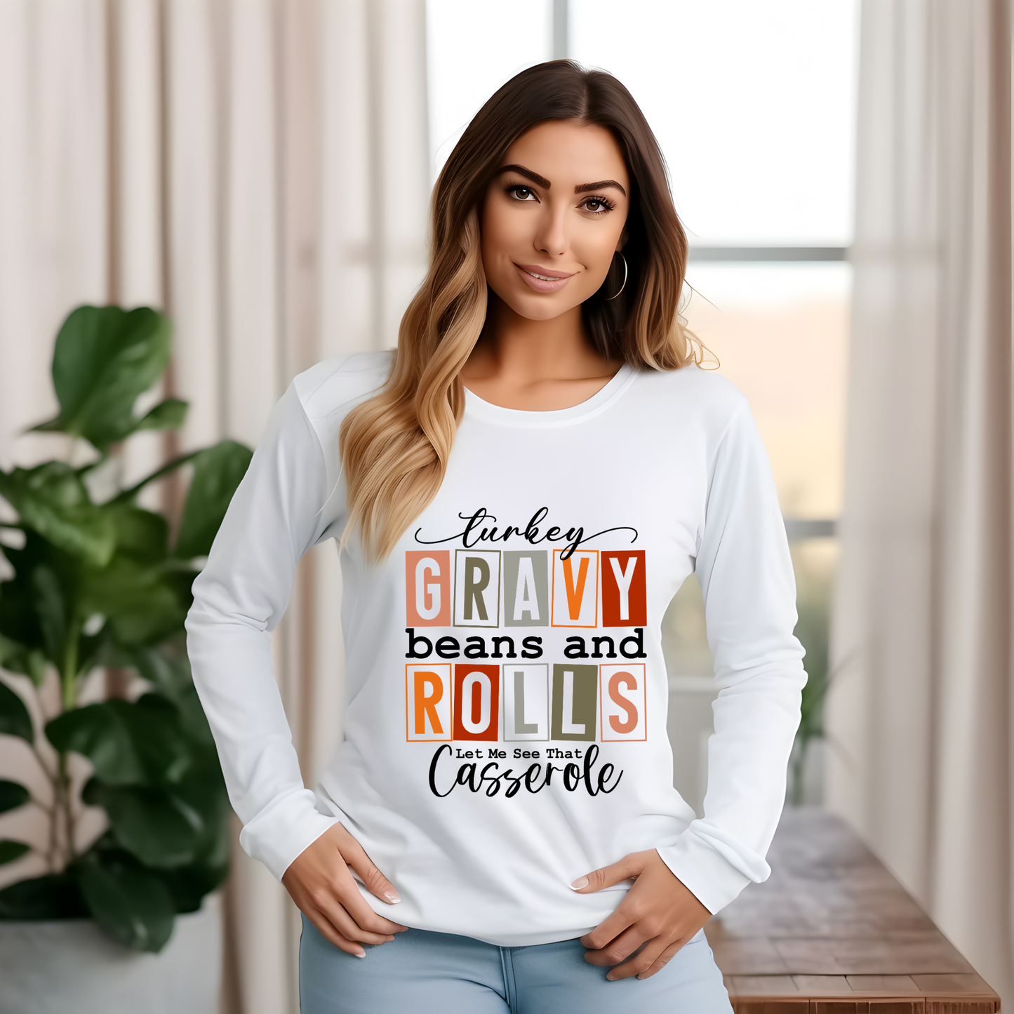 Woman wearing a white long-sleeve shirt with colorful text design in a home setting.