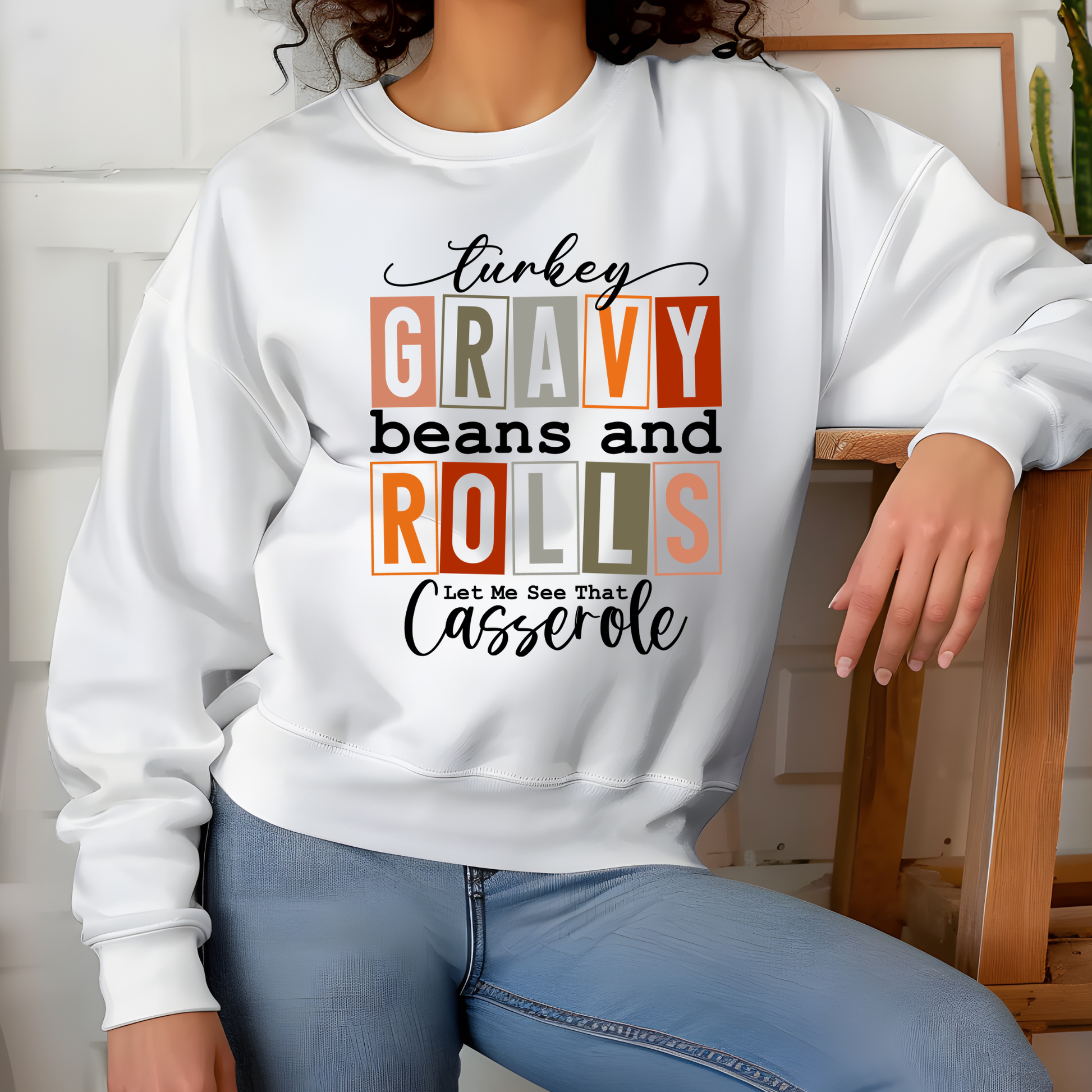 Person wearing a white sweatshirt with colorful text design sitting on a chair.