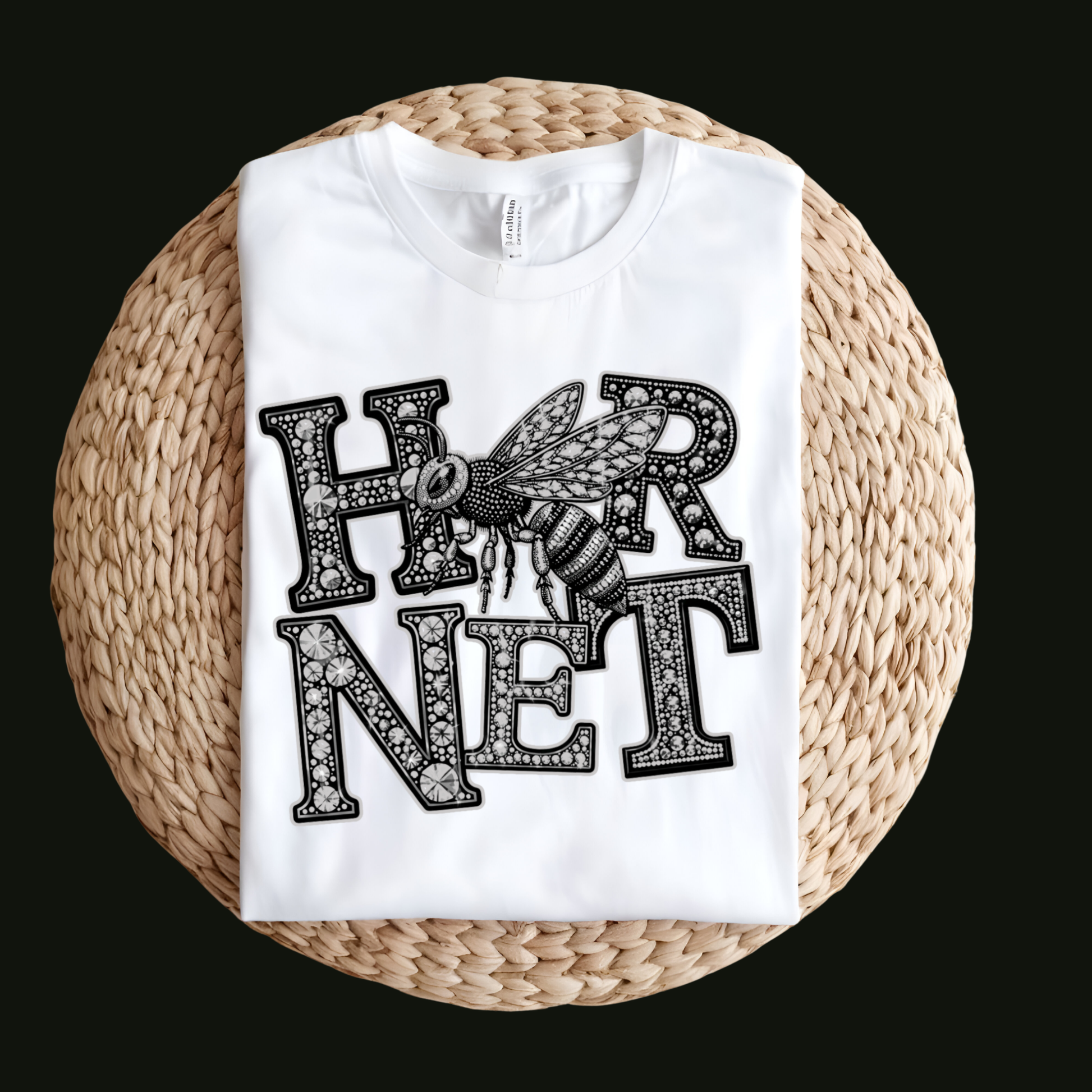A white short-sleeve T-shirt laid flat on a round woven straw mat against a black background. The shirt has a large front graphic reading “WE ARE Bulldogs” in distressed red, black, and white lettering.
