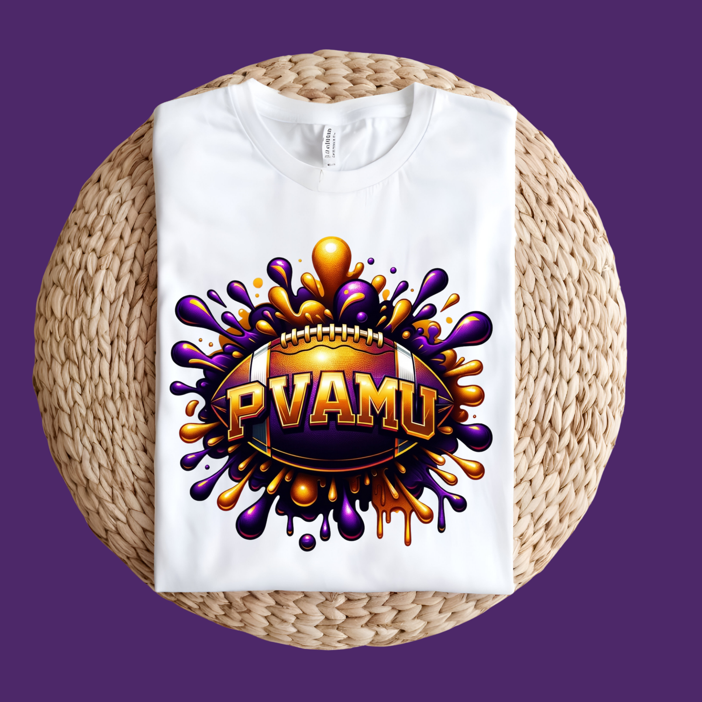 A white short-sleeve T-shirt laid flat on a round woven straw mat, featuring a large graphic of a purple and gold football player with the text 'PRAIRIE VIEW A&M PANTHERS' on the front, set against a solid purple background.