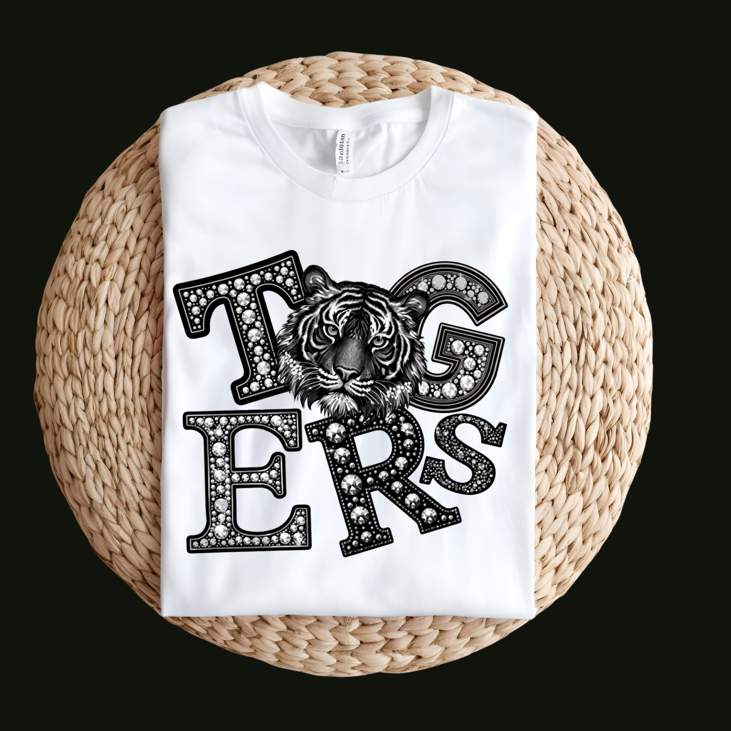 A white short-sleeve T-shirt laid flat on a round woven straw mat against a black background. The shirt has a large front graphic reading “WE ARE Bulldogs” in distressed red, black, and white lettering.