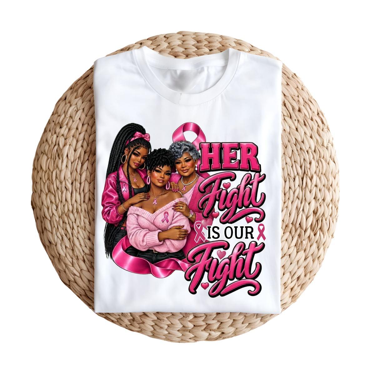 A folded white graphic T-shirt displayed on a round woven straw mat against a plain white background. The shirt features a large pink and black graphic with three illustrated women and the text 'HER Fight IS OUR Fight' with pink awareness ribbons.