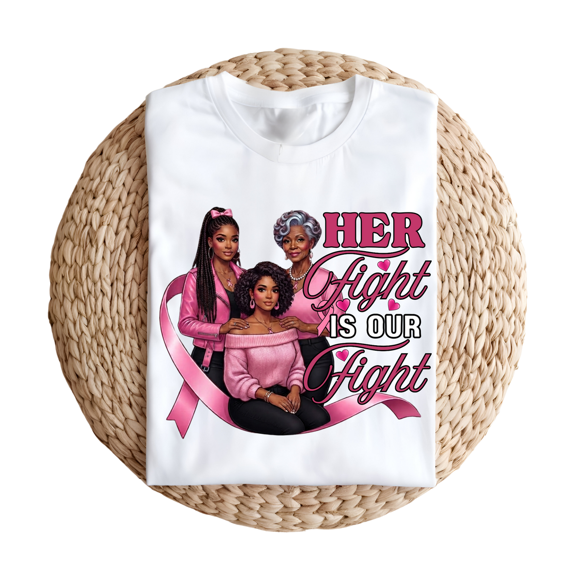 A white short-sleeve T-shirt laid flat on a round woven straw mat, featuring a large pink and black graphic that reads “I AM A SURVIVOR” with pink ribbons, butterflies, and hearts.