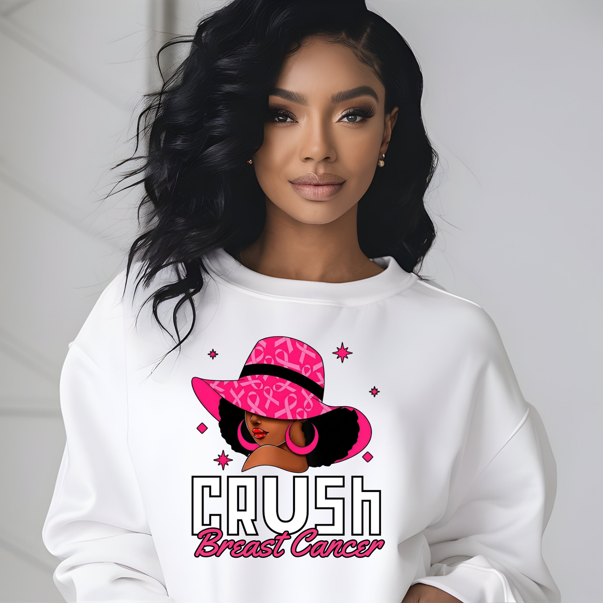 A woman wearing a white crewneck sweatshirt with a graphic print of a woman in a pink leopard-print hat and the text 'CRUSH Breast Cancer'.
