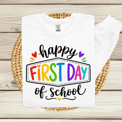 A white long-sleeve sweatshirt laid flat on a woven round mat over a light wood plank surface. The sweatshirt has a colorful graphic print reading “My Students Are The Reason” with a red apple icon and small heart accents.