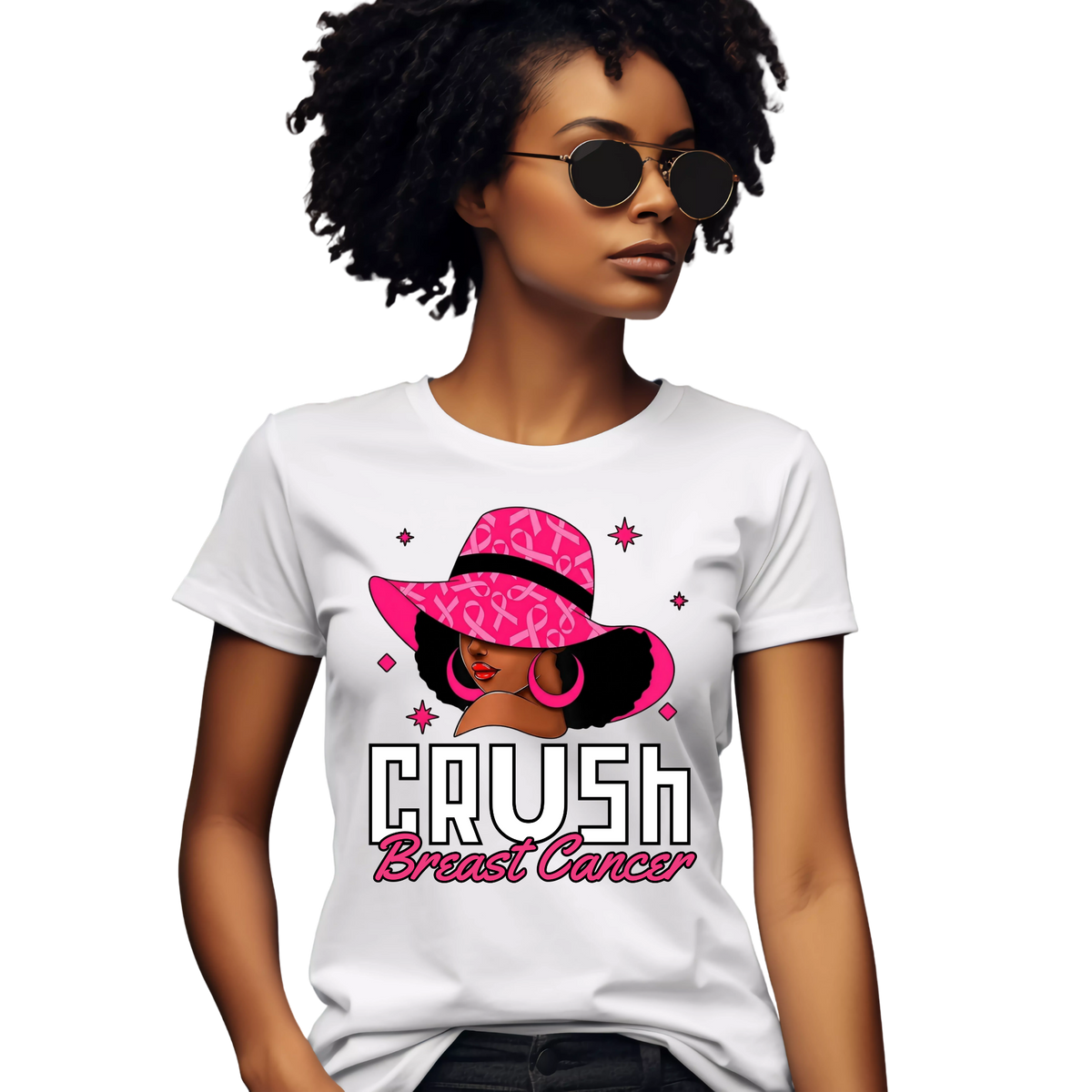 A woman wearing a white graphic T-shirt with a pink and black illustration of a woman in a pink hat and the text 'CRUSH Breast Cancer'.