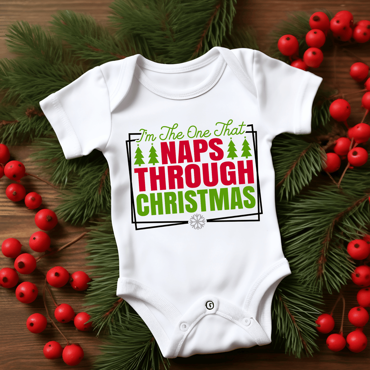 A white short-sleeve baby bodysuit with a Christmas-themed graphic print reading 'I'm The One That NAPS THROUGH CHRISTMAS' in green and red lettering, surrounded by pine branches and red berries on a wooden surface.