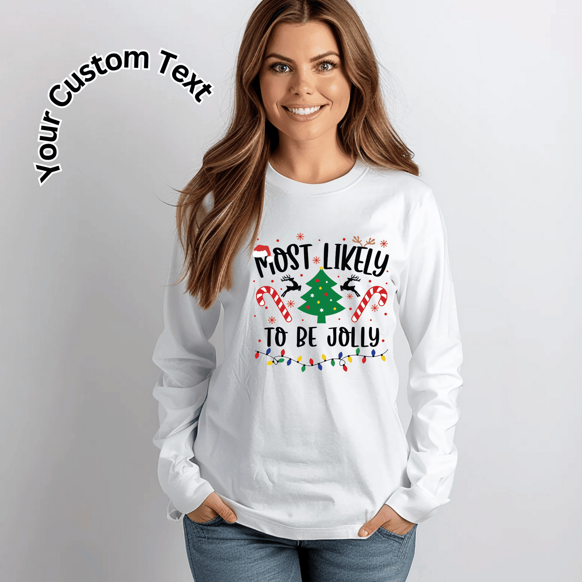 A woman wearing a white long-sleeve crewneck sweatshirt with a festive Christmas graphic that reads 'MOST LIKELY TO BE JOLLY' with a green Christmas tree, candy canes, and reindeer. The image has a light gray background, a 'Your Custom Text' graphic overlay in the top left, and the model is wearing blue jeans.