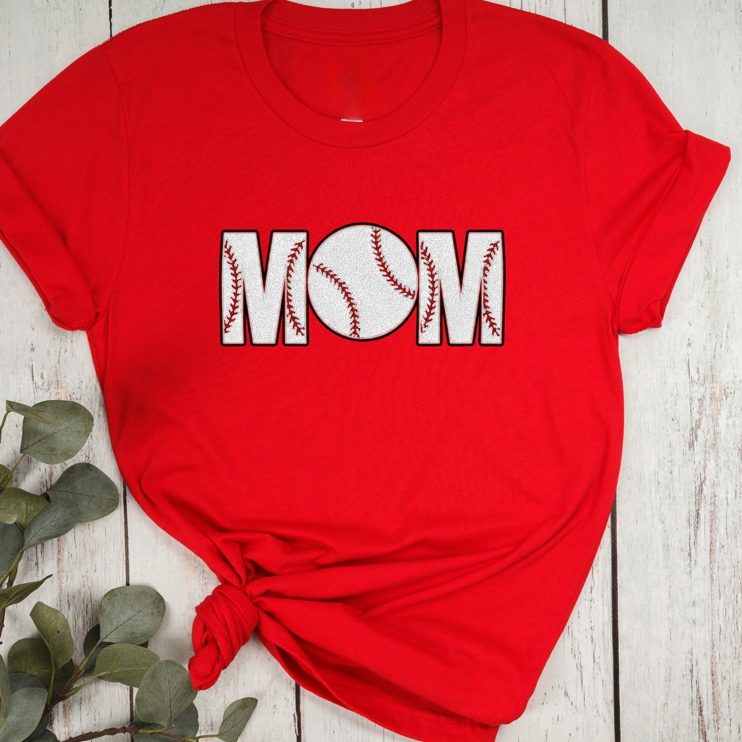 Red t-shirt with 'Mom' and baseball design on a wooden surface