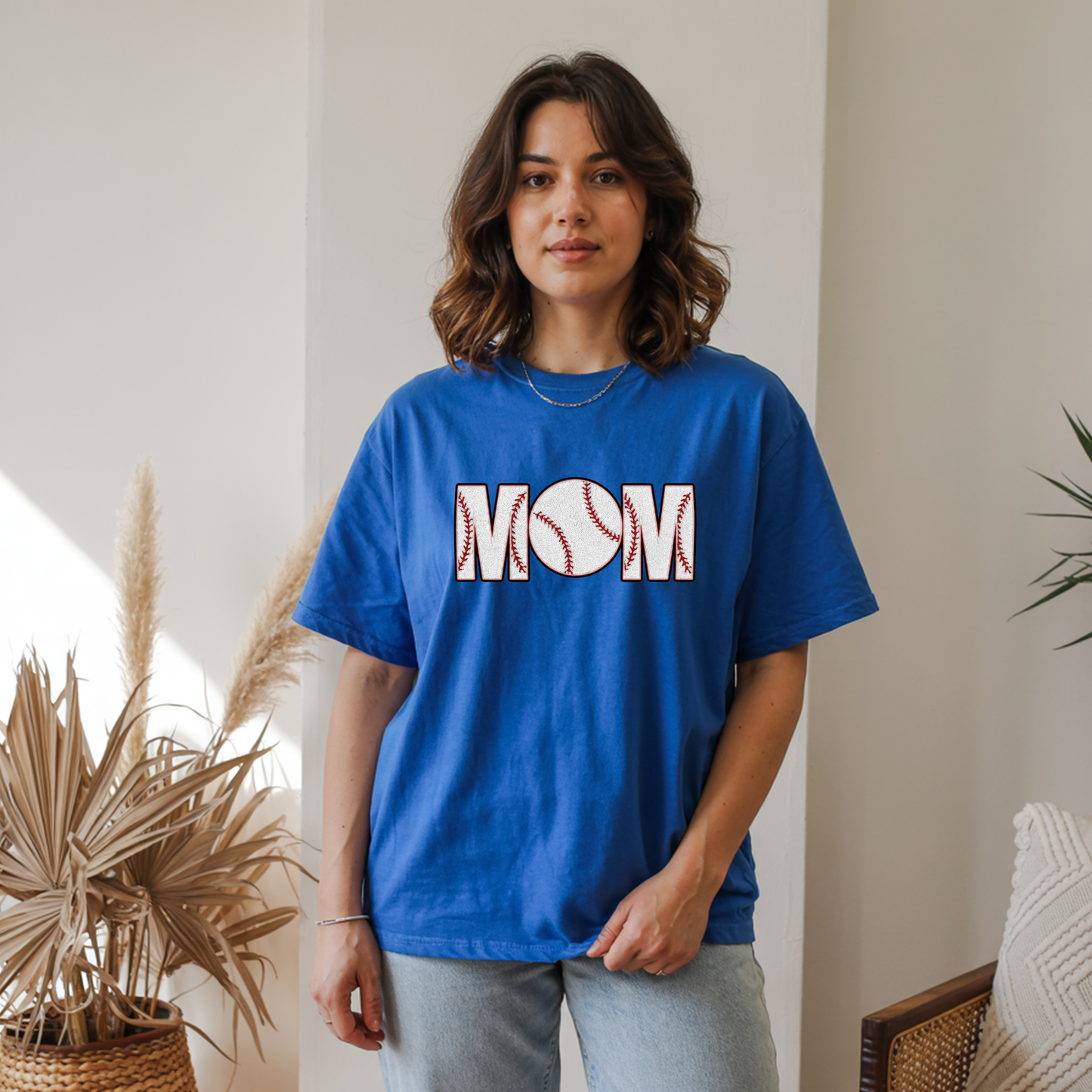 Woman wearing a blue t-shirt with 'MOM' and a baseball graphic indoors.