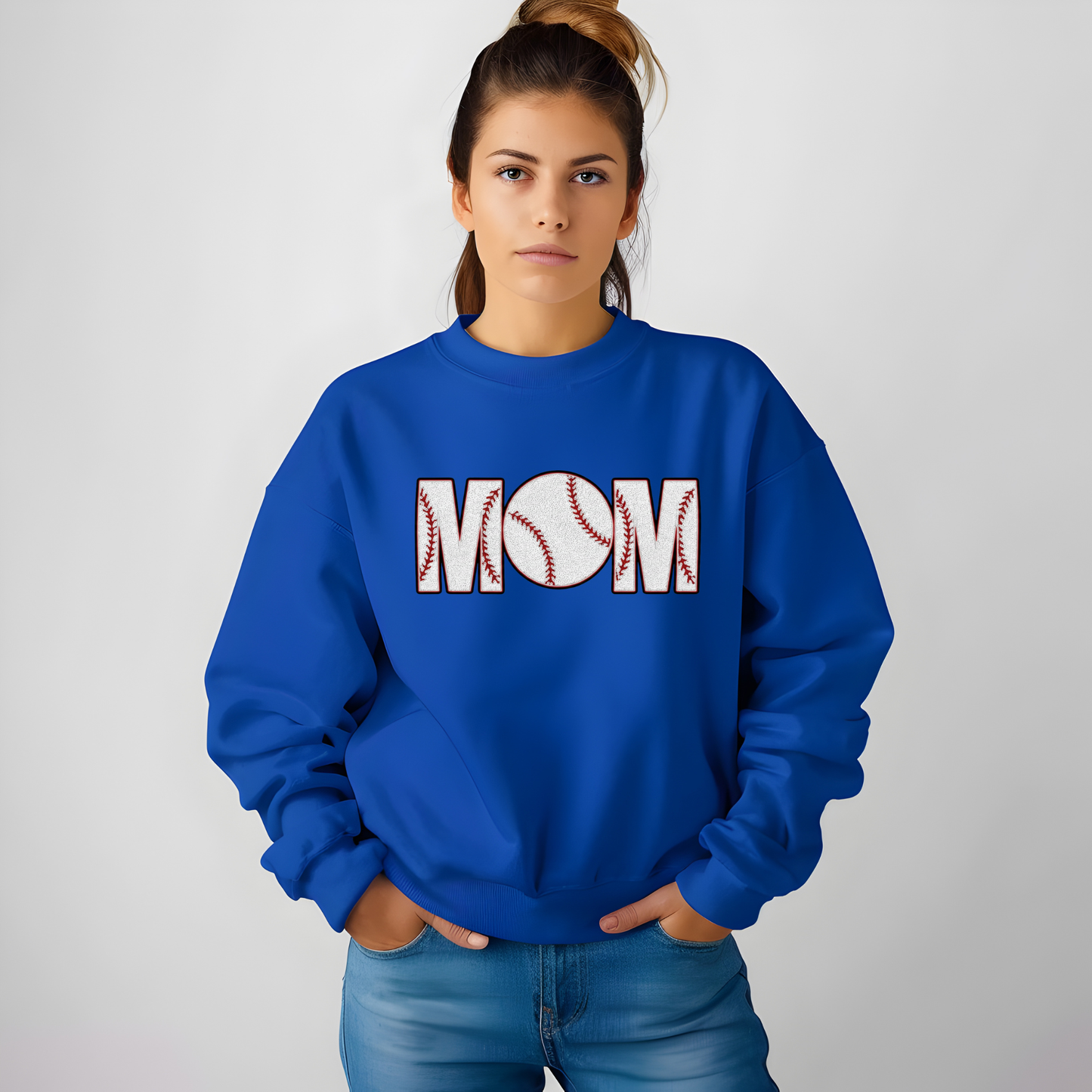 Person wearing a blue sweatshirt with 'MOM' and a baseball design on a plain background