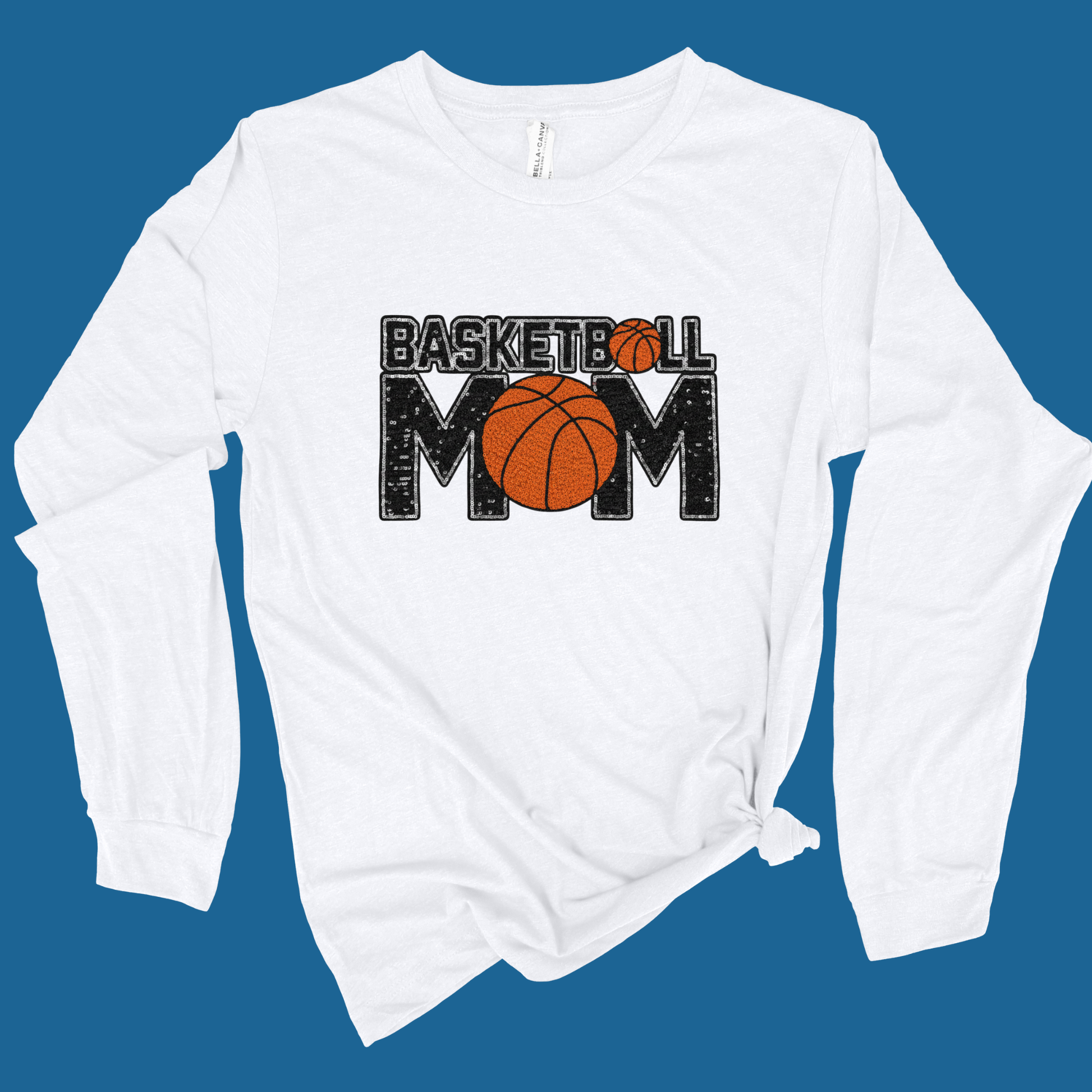 White long-sleeve shirt with 'Basketball Mom' text and basketball graphic on a blue background