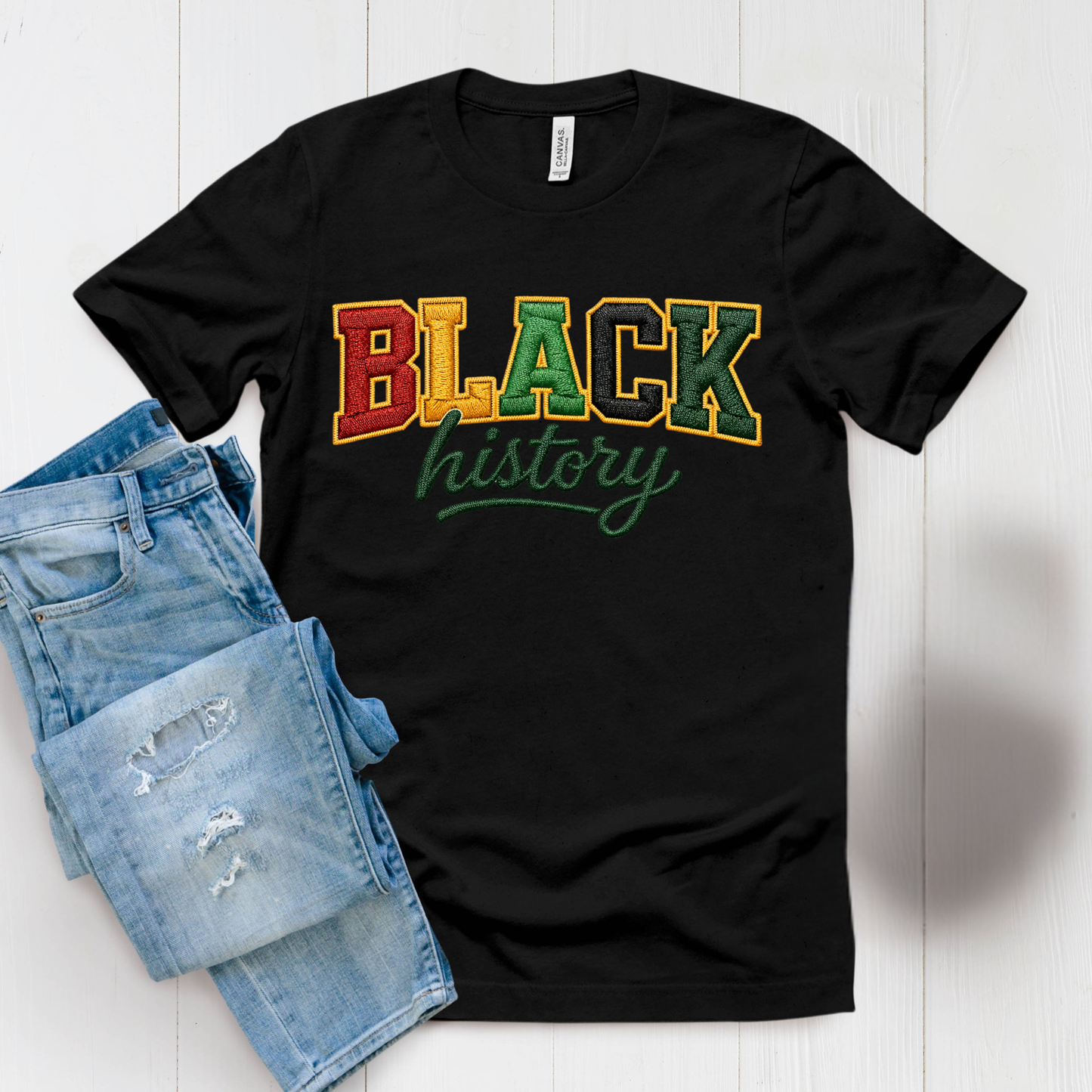 Black t-shirt with 'BLACK history' text in multicolor on a white surface with denim shorts.