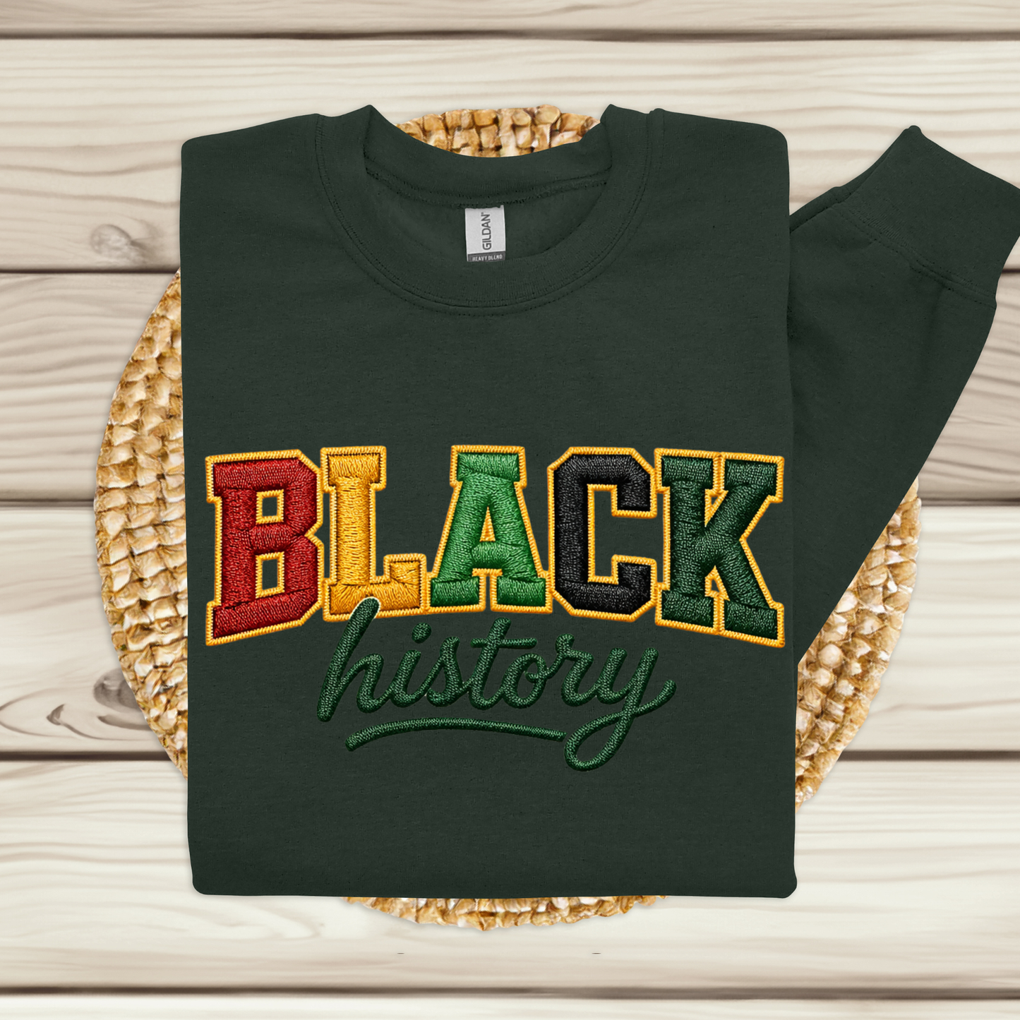 Black sweatshirt with 'BLACK history' text in multicolor on a woven mat.