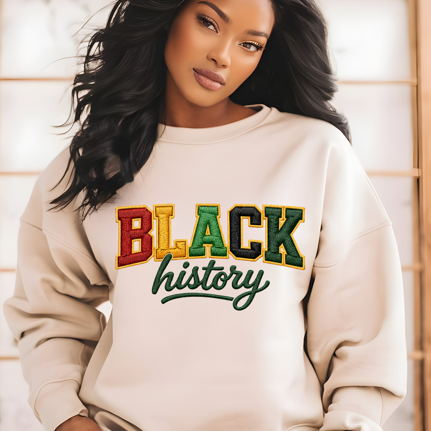 Woman wearing a beige sweatshirt with 'BLACK history' text in multicolors.