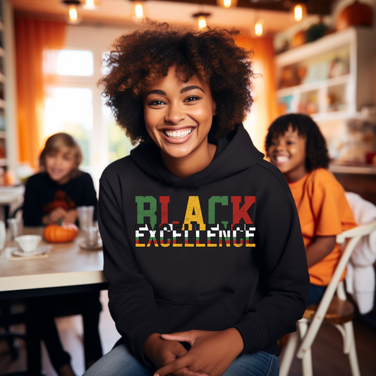 Person wearing a black hoodie with 'BLACK EXCELLENCE' in colorful letters, sitting in a casual indoor setting.