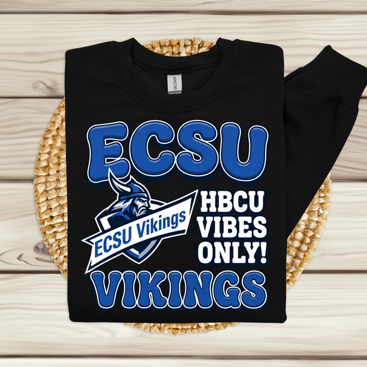 A black long-sleeve sweatshirt with a blue and white ECSU Vikings graphic, displayed flat on a woven placemat over a light wood background.