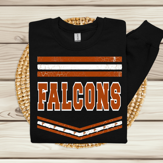 A black long-sleeve t-shirt with a distressed orange and white 'FALCONS' graphic, folded and displayed on a round woven placemat over a light wood plank background.