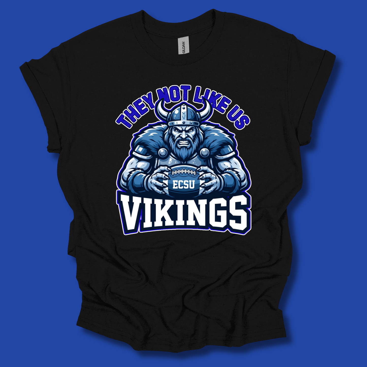 A black short-sleeve t-shirt with a graphic of a blue and white Viking holding an EC SU football, with the text 'THEY NOT LIKE US' above and 'VIKINGS' below, displayed against a solid blue background.