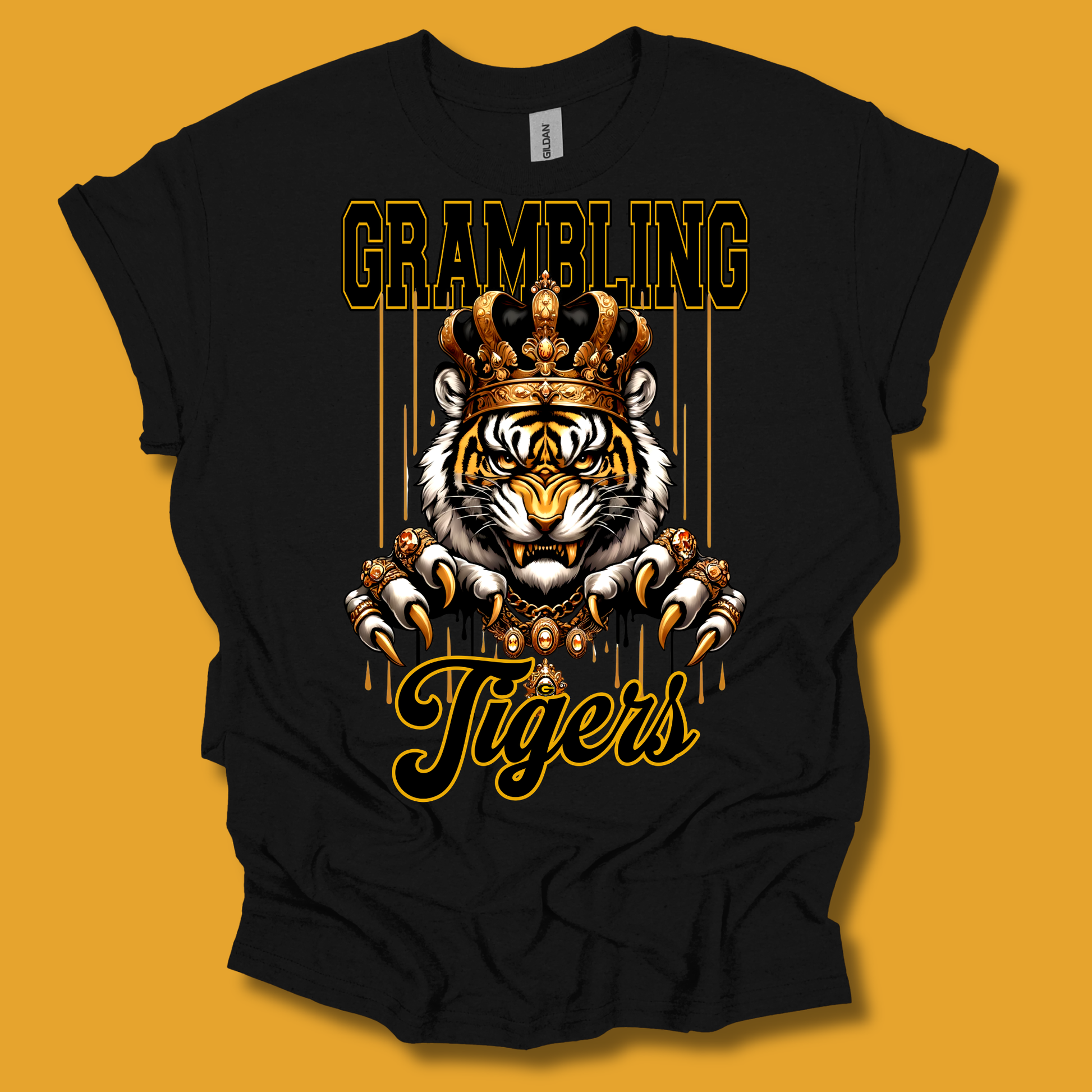 A black short-sleeve t-shirt with a graphic print of a tiger wearing a crown, with the text 'GRAMBLING' above and 'Tigers' below, displayed against a solid orange background.