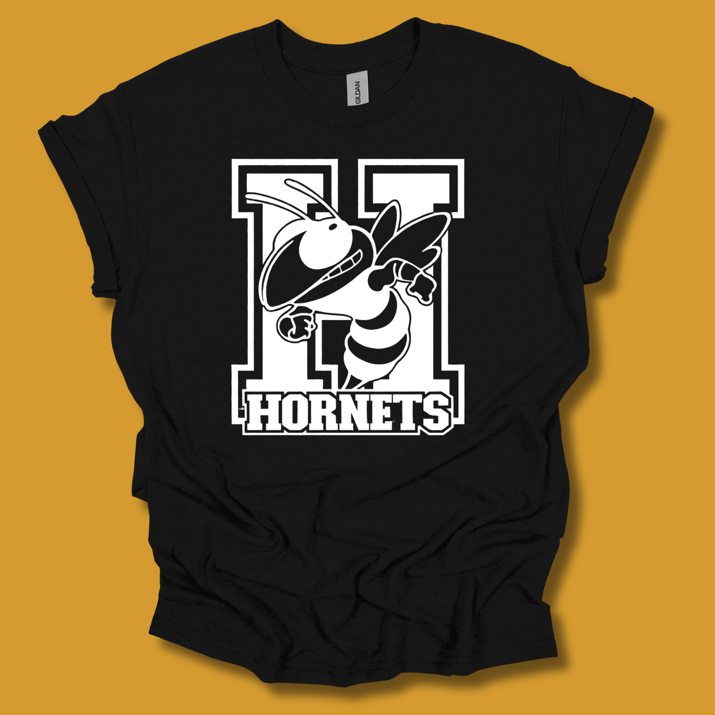A black short-sleeve t-shirt with a large white and black 'H Hornets' graphic on the front, displayed against a solid mustard yellow background.