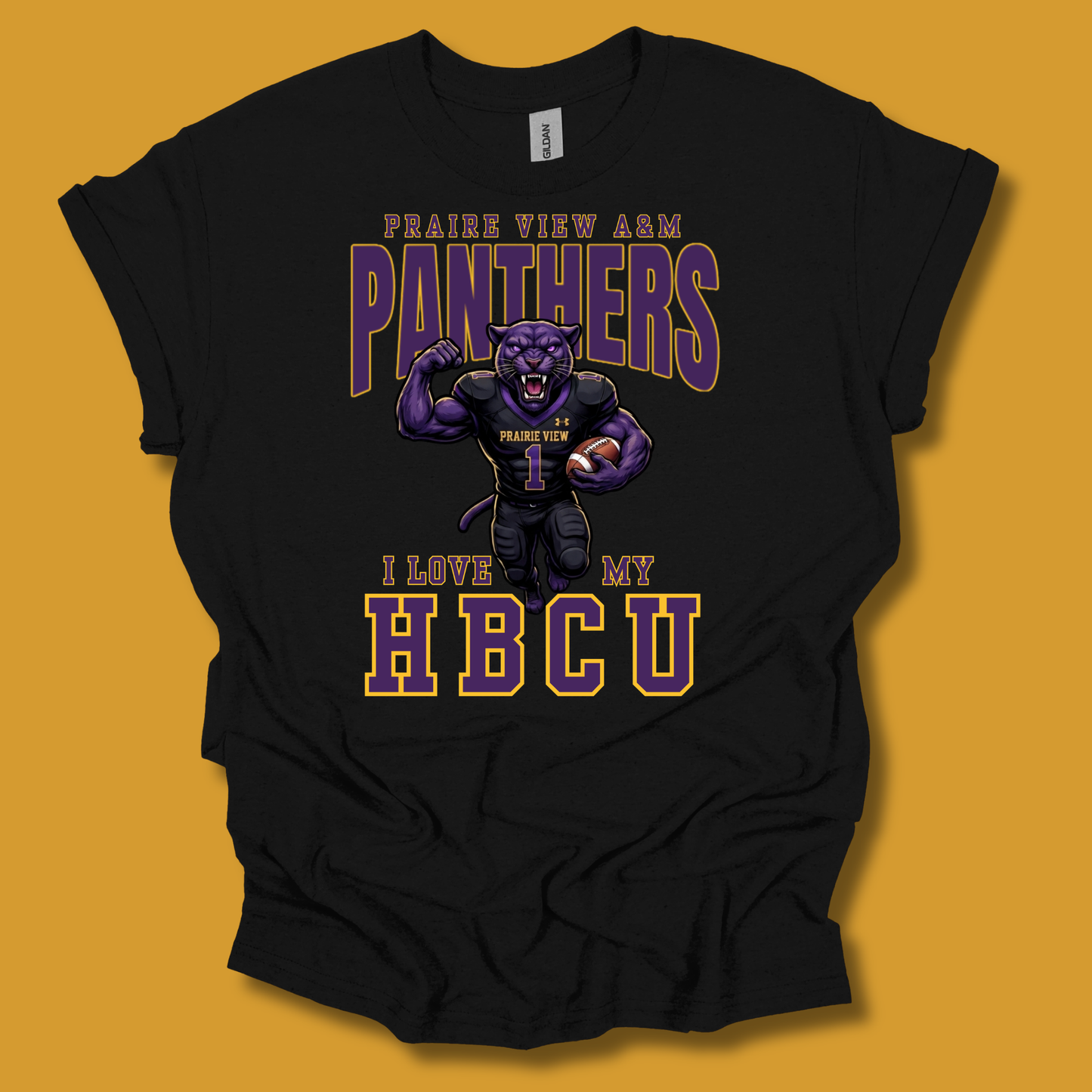 A black short-sleeve graphic t-shirt featuring a purple and gold design with the text 'PRAIRIE VIEW A&M PANTHERS I LOVE MY HBCU' and an illustration of a panther mascot, shown against a solid mustard yellow background.