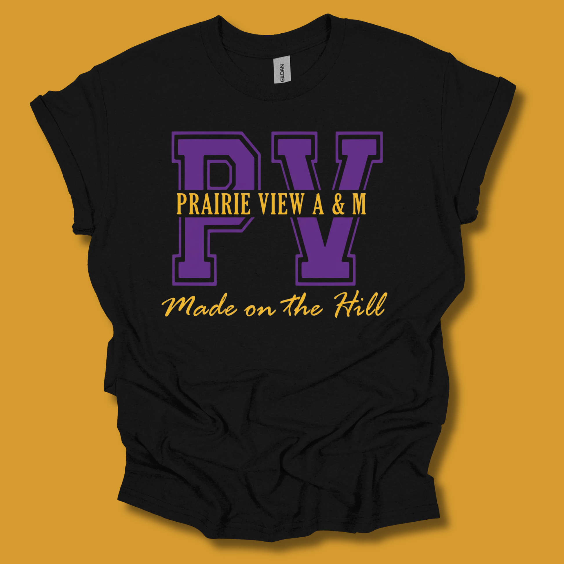 A black short-sleeve t-shirt with a purple and yellow graphic print reading 'PV PRAIRIE VIEW A & M Made on the Hill' on a mustard yellow background.