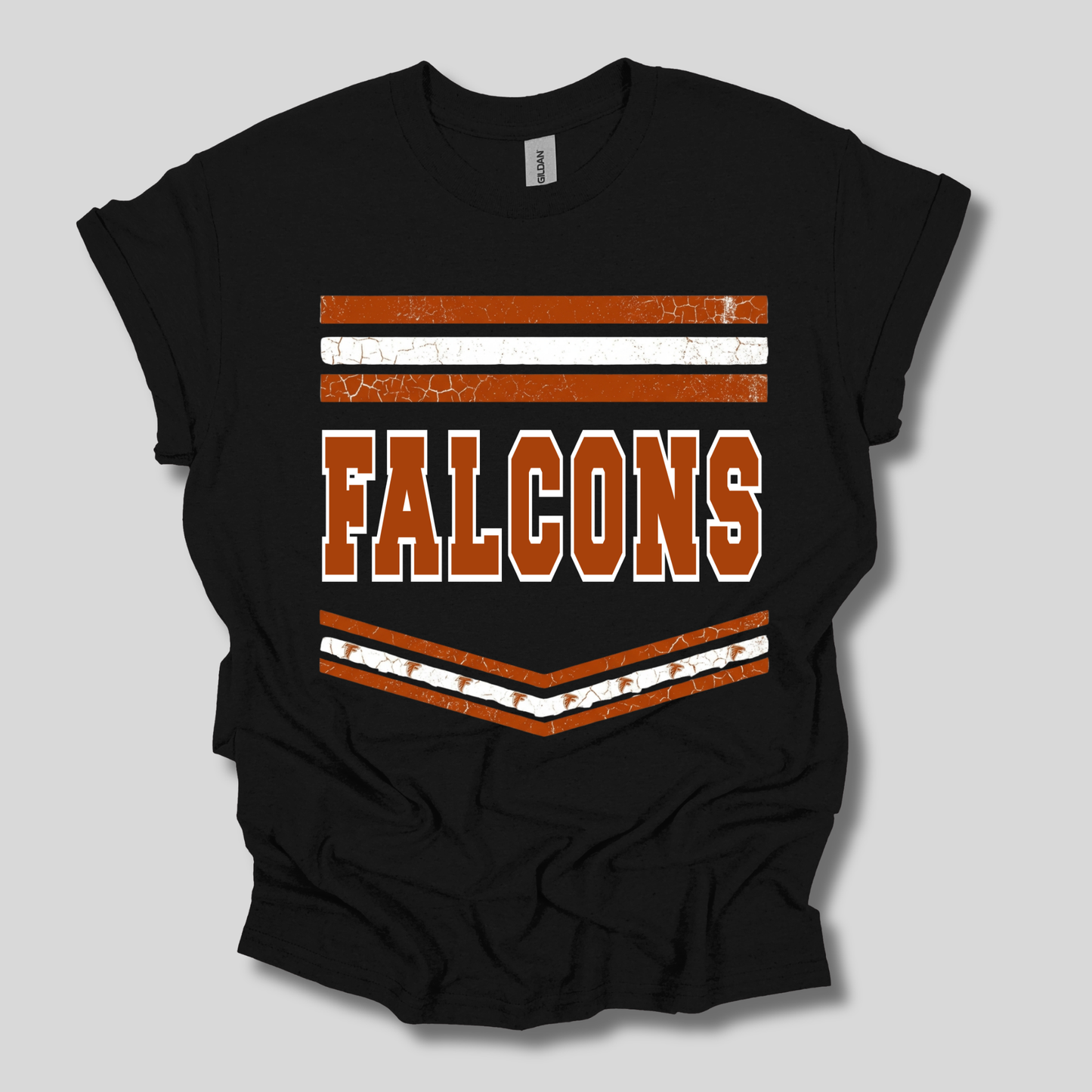 A black short-sleeve t-shirt with a distressed orange and white graphic on the front featuring the word 'FALCONS' and chevron stripes, displayed on a neutral gray background.