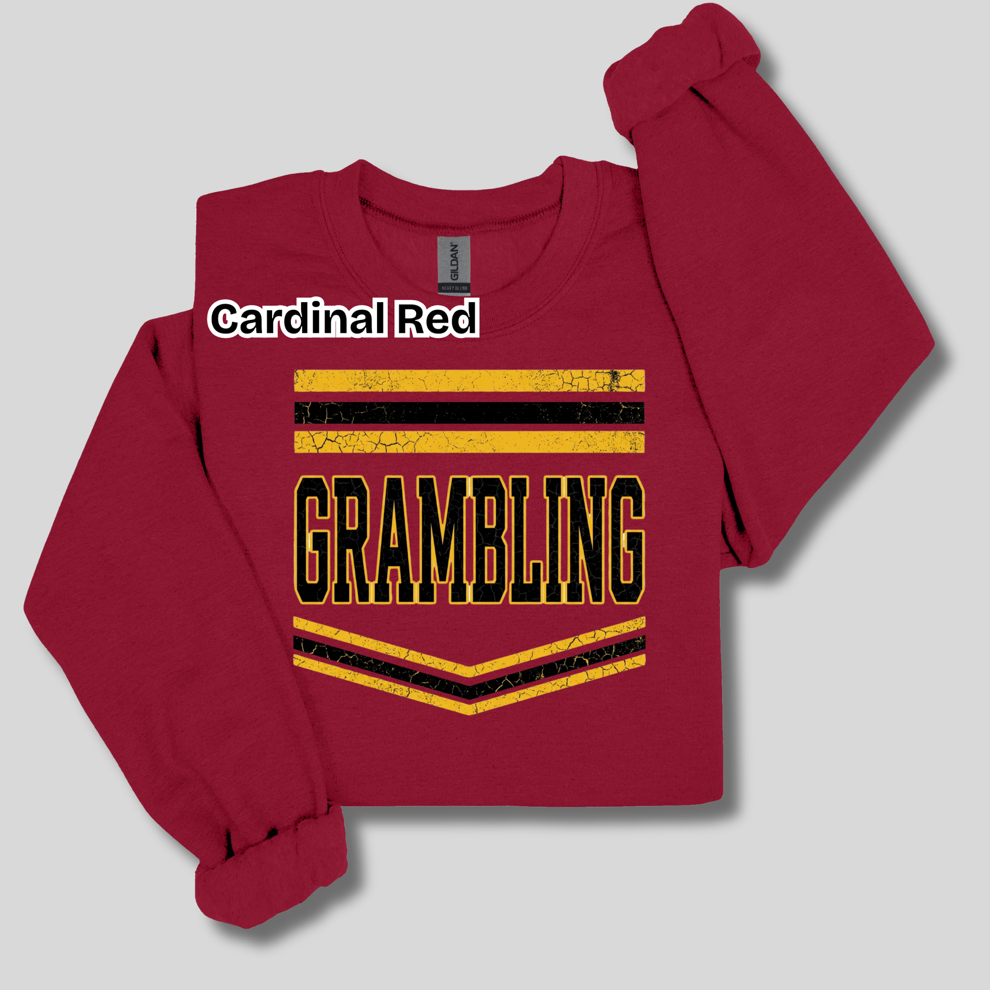 A long-sleeve crewneck sweatshirt in Cardinal Red, featuring a distressed yellow and black 'GRAMBLING' graphic on the front with a white text label overlay reading 'Cardinal Red'.