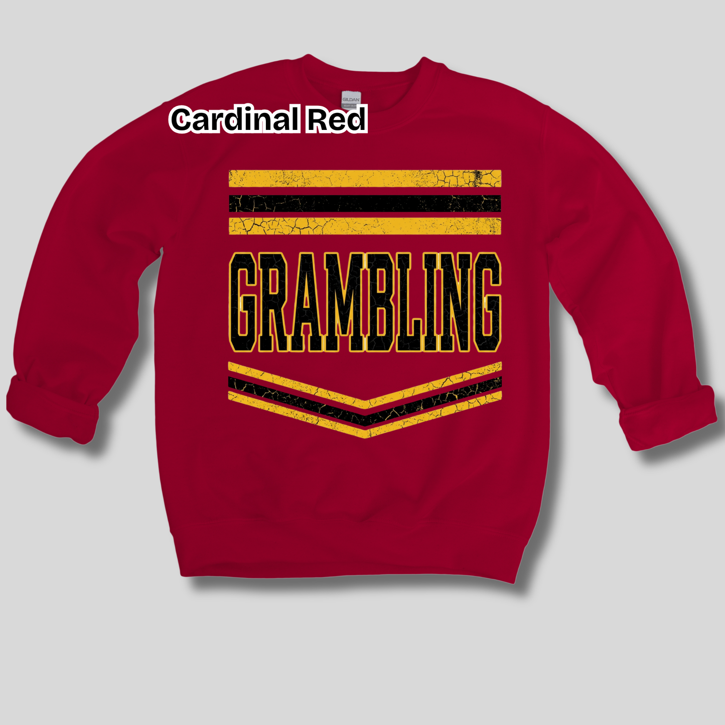 A red crewneck sweatshirt with a distressed yellow and black 'GRAMBLING' graphic on the front, featuring horizontal and chevron stripes. The text 'Cardinal Red' is printed in white near the upper left chest, and the sweatshirt is displayed against a neutral gray background.