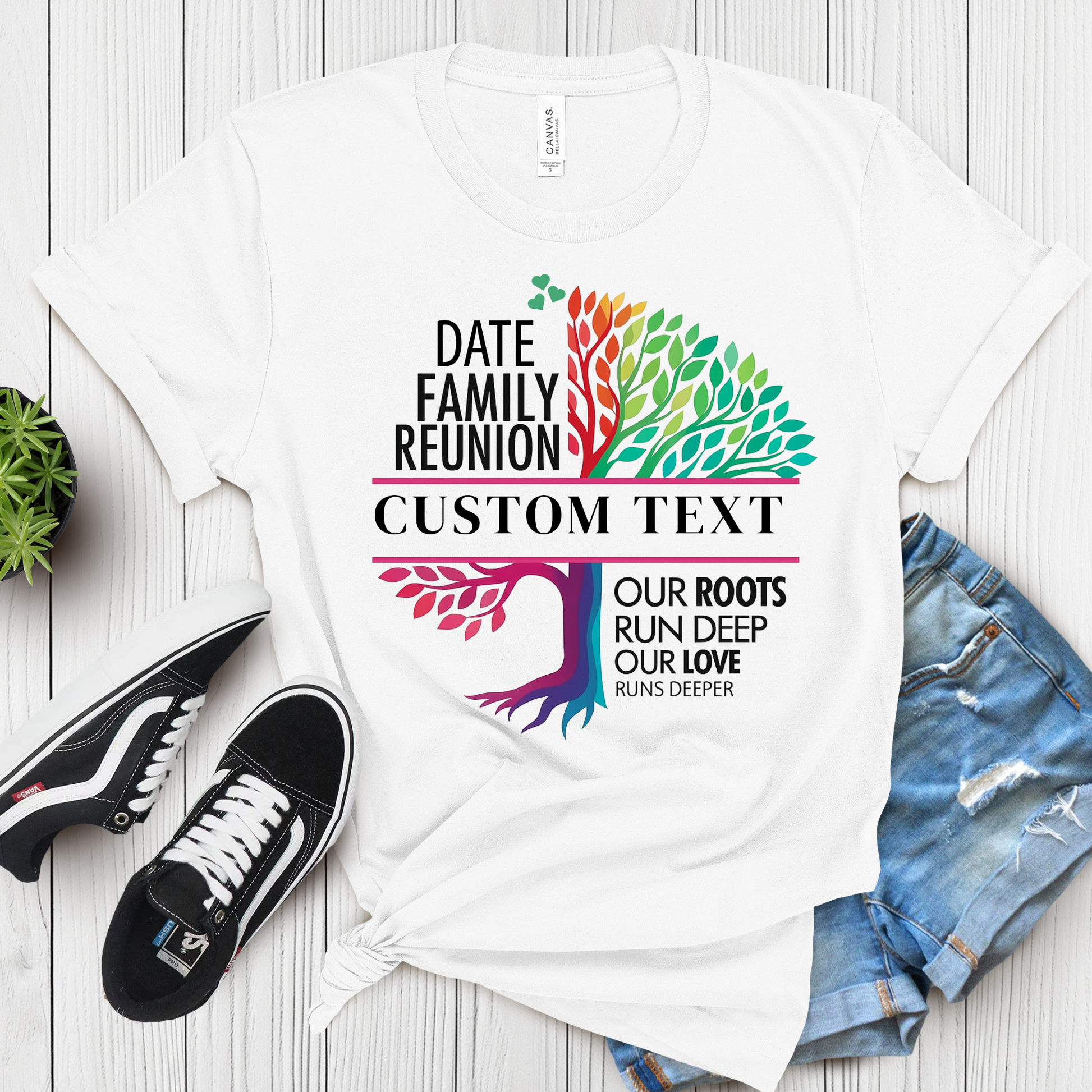 White t-shirt with colorful family reunion design on a wooden surface with shoes and shorts.