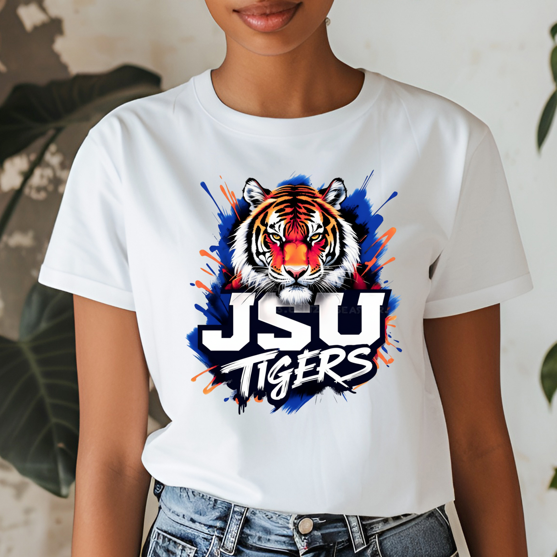 A woman wearing a white graphic t-shirt with a purple and gold print that reads 'PRAIRE VIEW A&M PANTHERS I LOVE MY HBCU' with an illustration of a running panther football player.