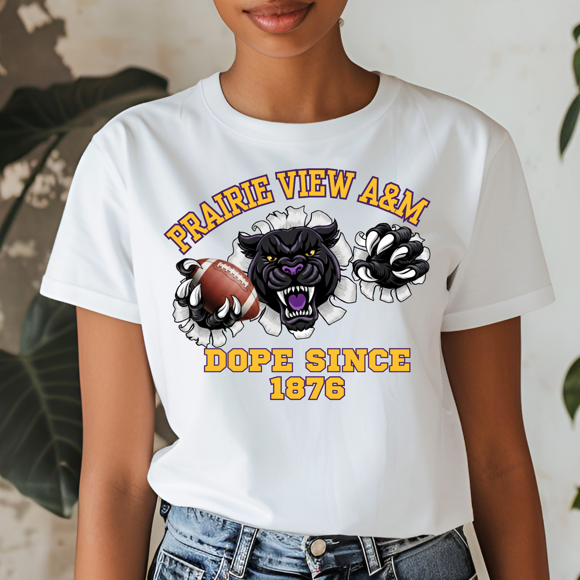 A woman wearing a white graphic t-shirt featuring a black panther mascot, a football, and the text 'PRAIRIE VIEW A&M DOPE SINCE 1876'.
