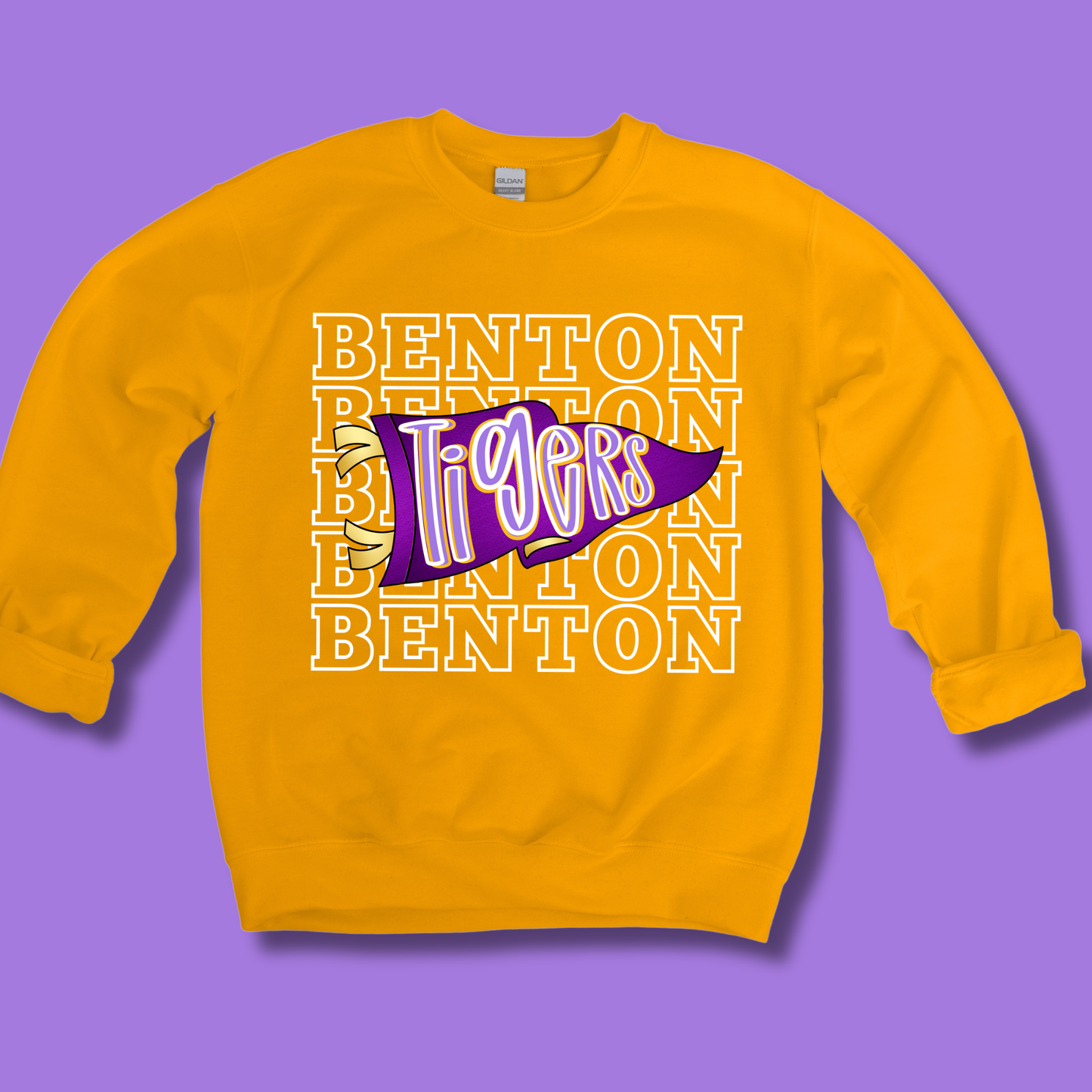 A yellow crewneck sweatshirt featuring a purple and white 'Benton Tigers' graphic on the front, set against a solid purple background.